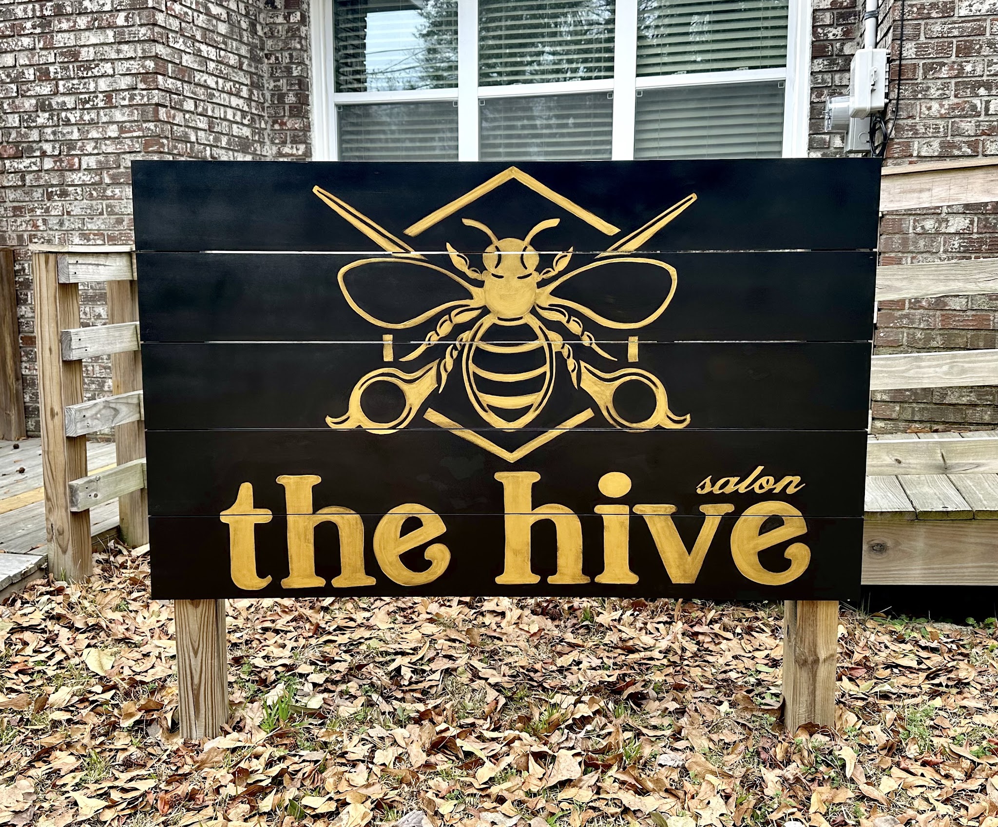 The hand-painted black and gold Hive Salon sign outside the salon